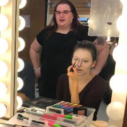 Allison Lowery overseeing a student putting on makeup